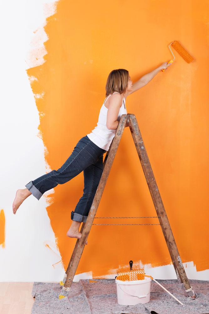 Woman,Stands,On,A,Ladder,To,Paint,Her,Walls,Orange