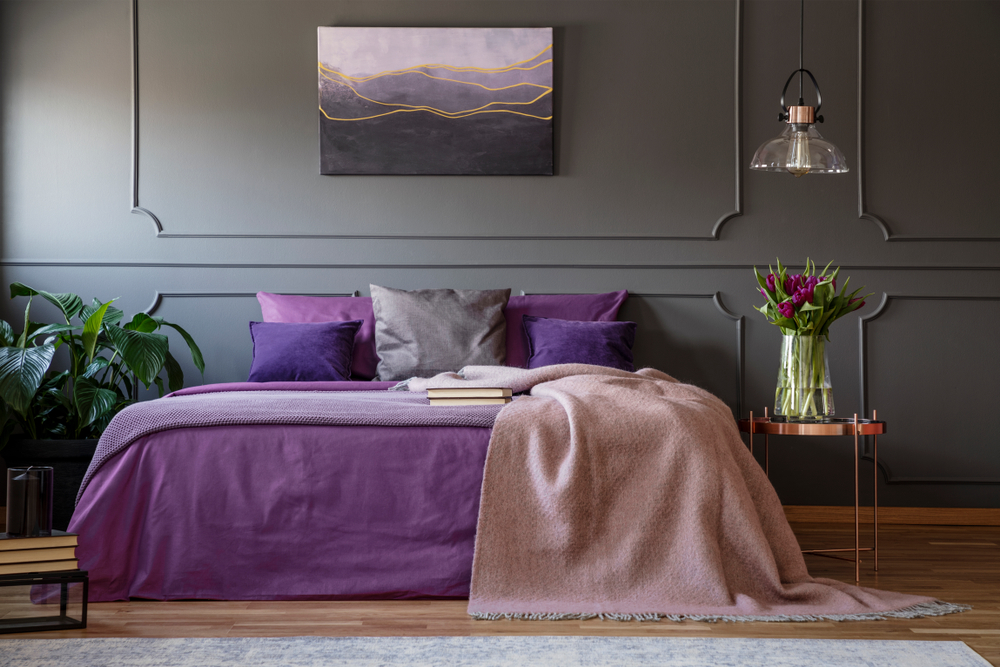 Lamp,Above,Copper,Table,With,Flowers,Next,To,Bed,With