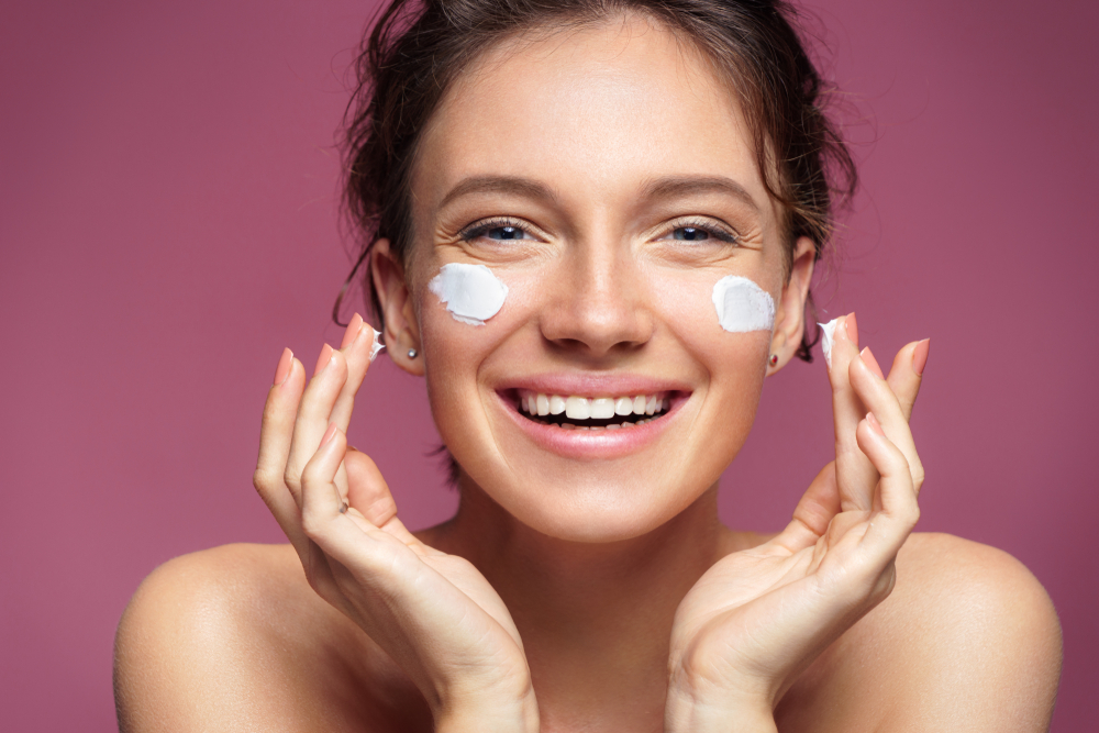 Laughing,Girl,Applying,Moisturizing,Cream,On,Her,Face.,Photo,Of