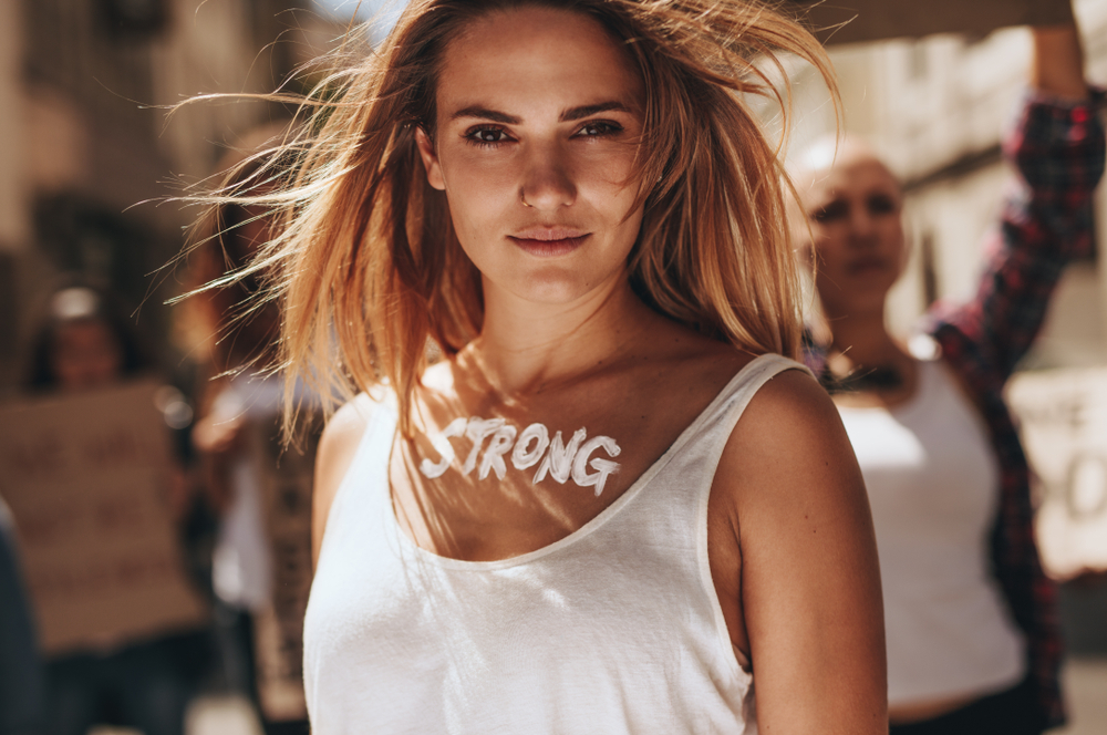 Confident,Female,Activist,Protesting,Outdoors,With,Group,Of,Women,In