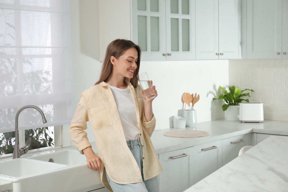 Woman,Drinking,Tap,Water,From,Glass,In,Kitchen