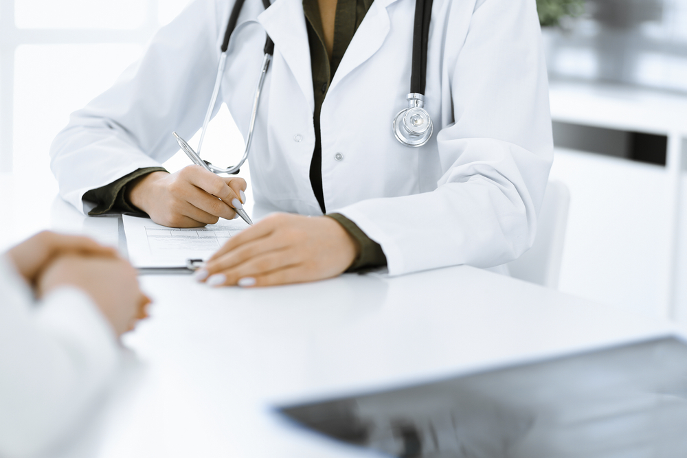 Unknown,Woman-doctor,And,Female,Patient,Sitting,And,Talking,At,Medical