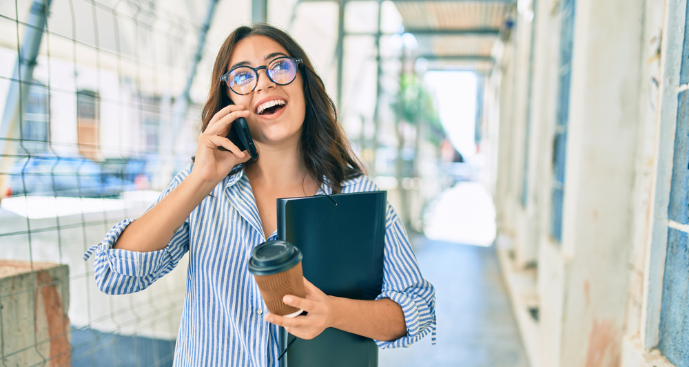 Young,Hispanic,Businesswoman,Smiling,Happy,Talking,On,The,Smartphone,At
