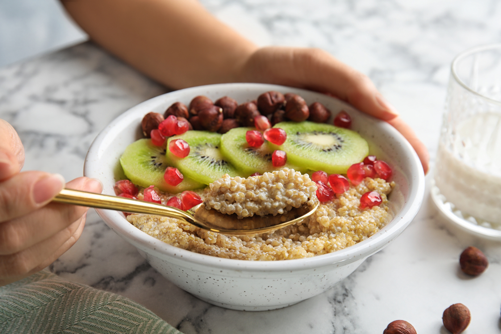 Woman,Eating,Quinoa,Porridge,With,Hazelnuts,,Kiwi,And,Pomegranate,Seeds