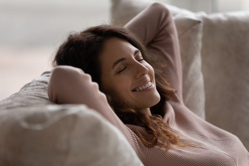 Smiling,Young,Hispanic,Woman,Lying,Resting,On,Couch,At,Home