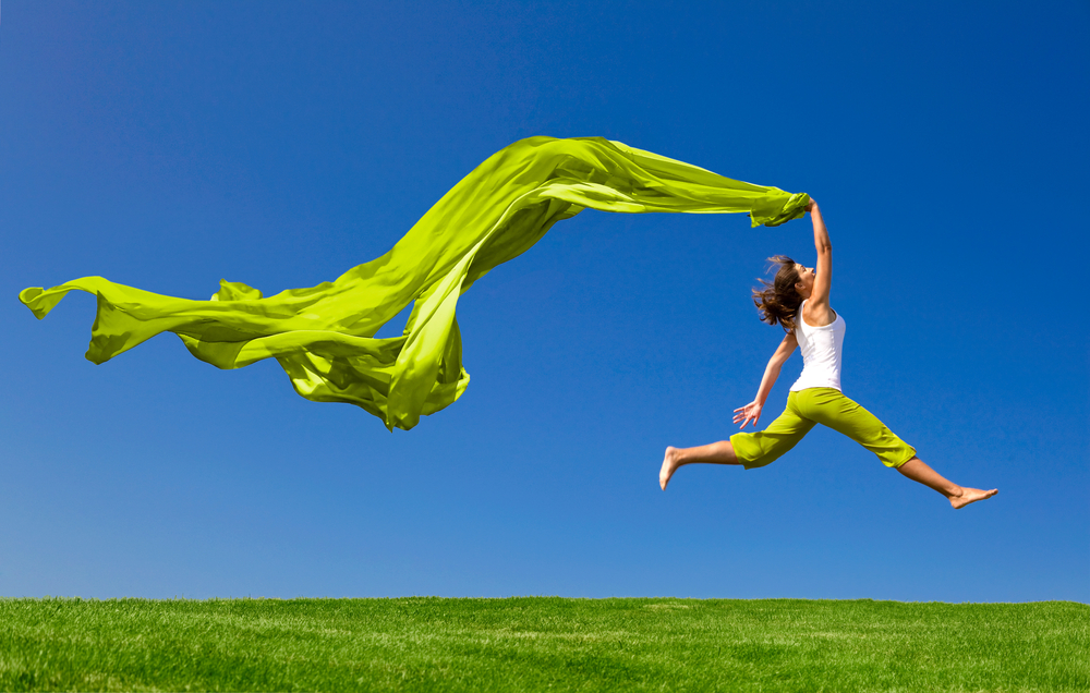 Beautiful,Young,Woman,Jumping,On,A,Green,Meadow,With,A
