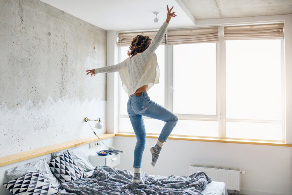 Young,Happy,Woman,Jumping,On,Bed,In,Morning,,Stylish,Bedroom,