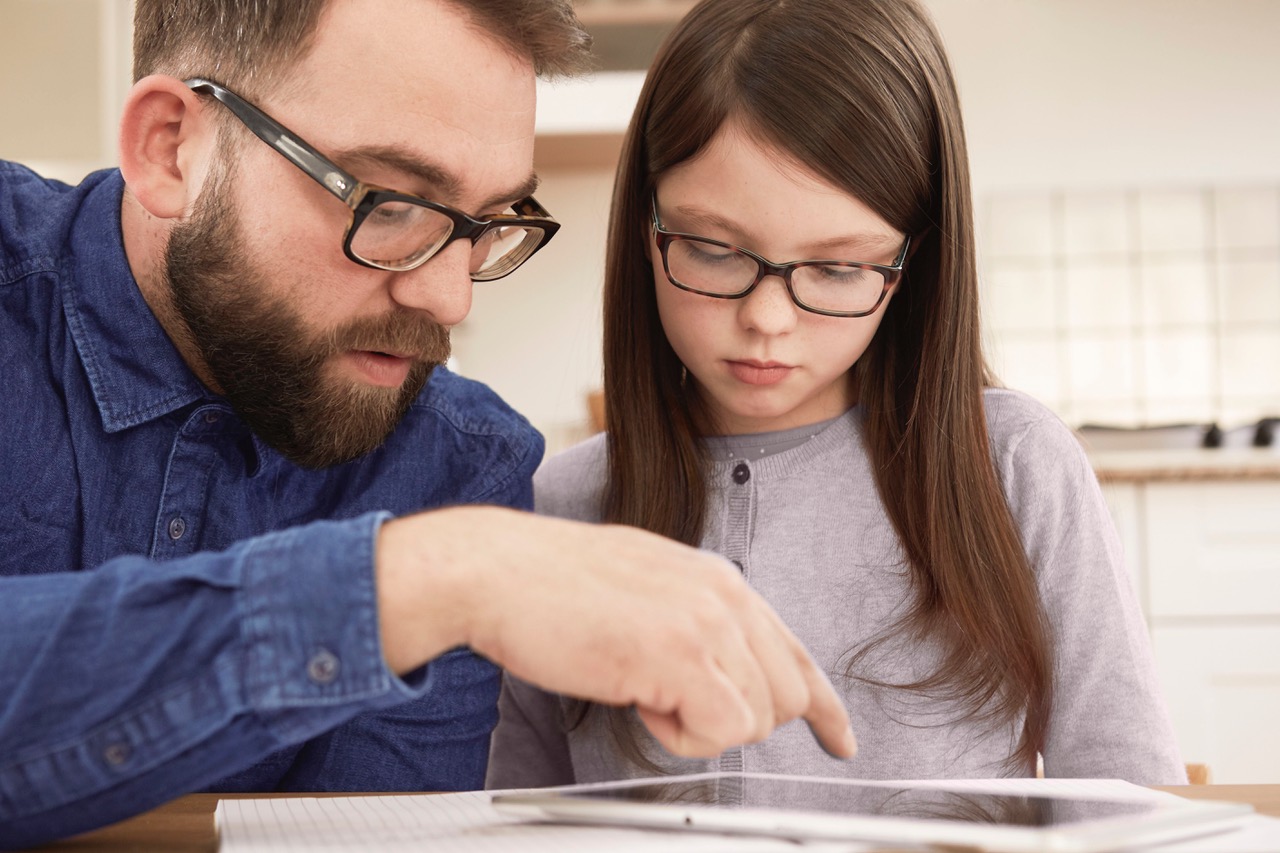Mid adult man explaining homework to daughter at table