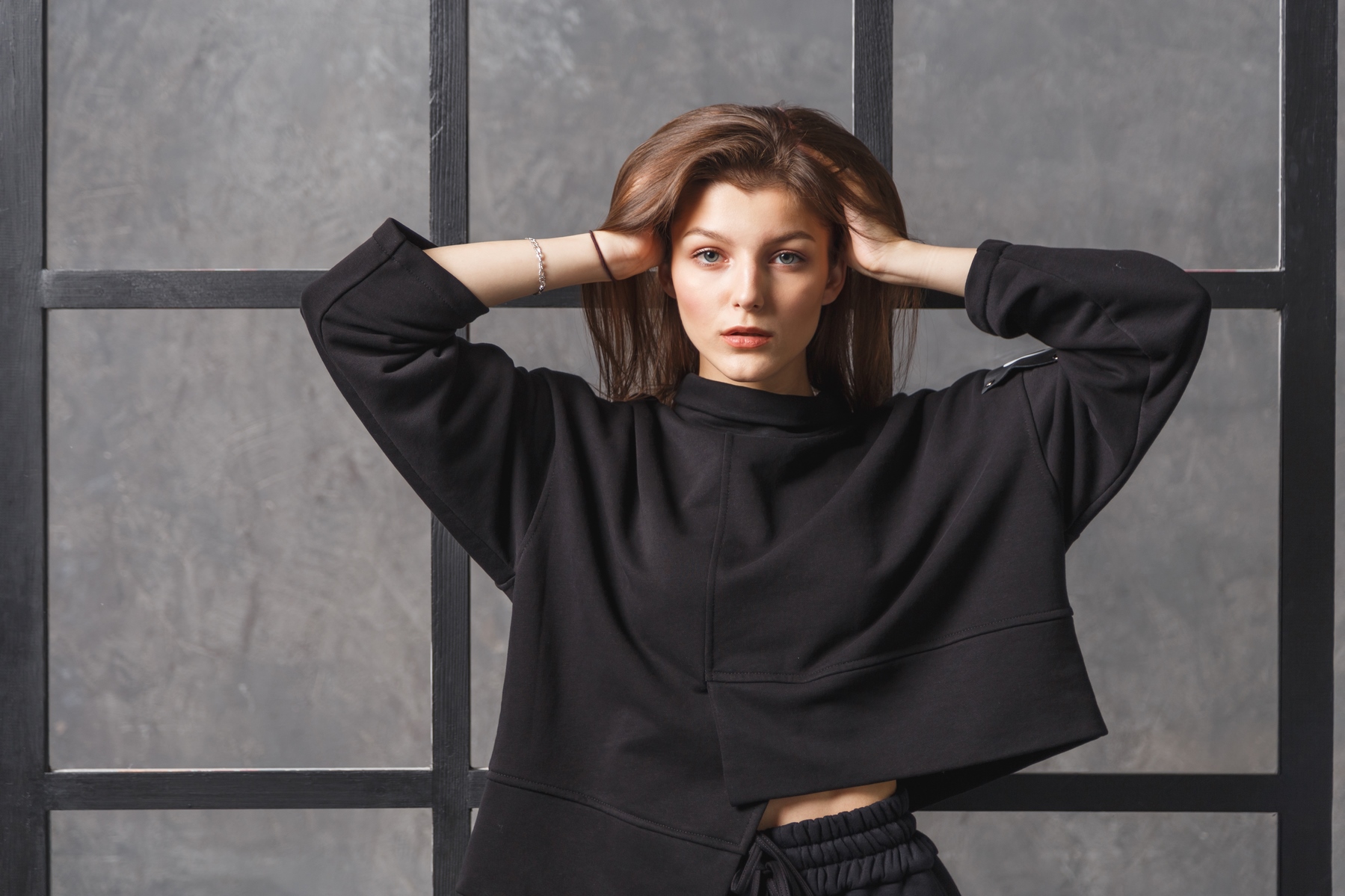 Young woman in black sportswear, pants and sweatshirt. Concept of fashionable sport outfit, indoors photo. Copy space.