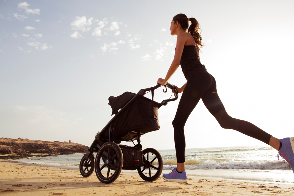 Young,Mom,Is,Running,With,Stroller,On,The,Beach.
