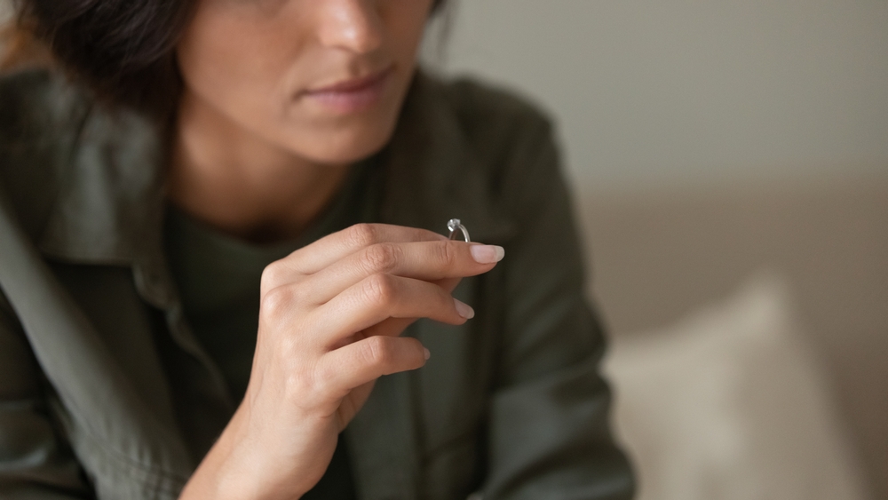 Depressed,Sad,Young,Woman,Taking,Off,And,Holding,Wedding,Ring.