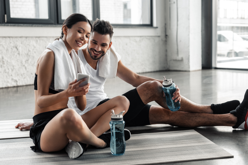 Happy,Sporty,Young,Couple,Resting,On,Yoga,Mats,And,Using