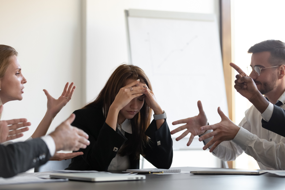 Frustrated,Millennial,Female,Worker,Sitting,At,Table,With,Colleagues,,Felling