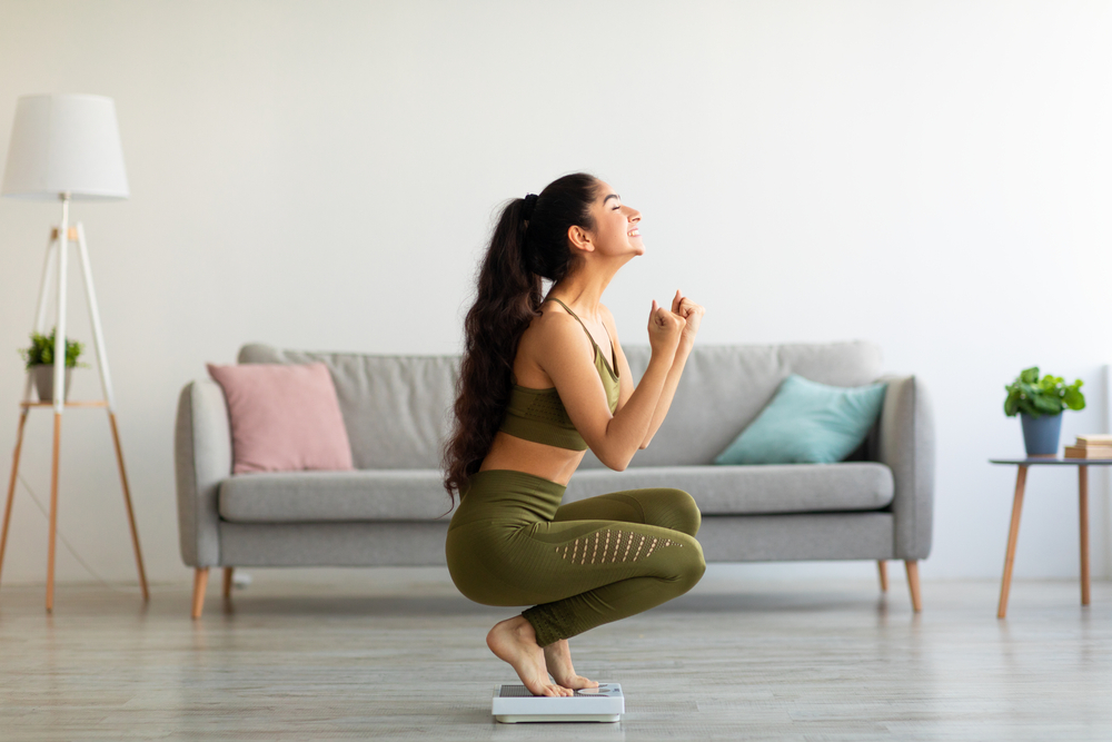 Full,Length,Of,Excited,Indian,Woman,Sitting,On,Scales,At