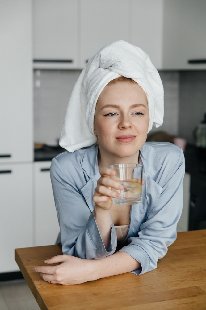 Young,Woman,Dressed,In,Pajamas,Drinking,Water,With,A,Piece