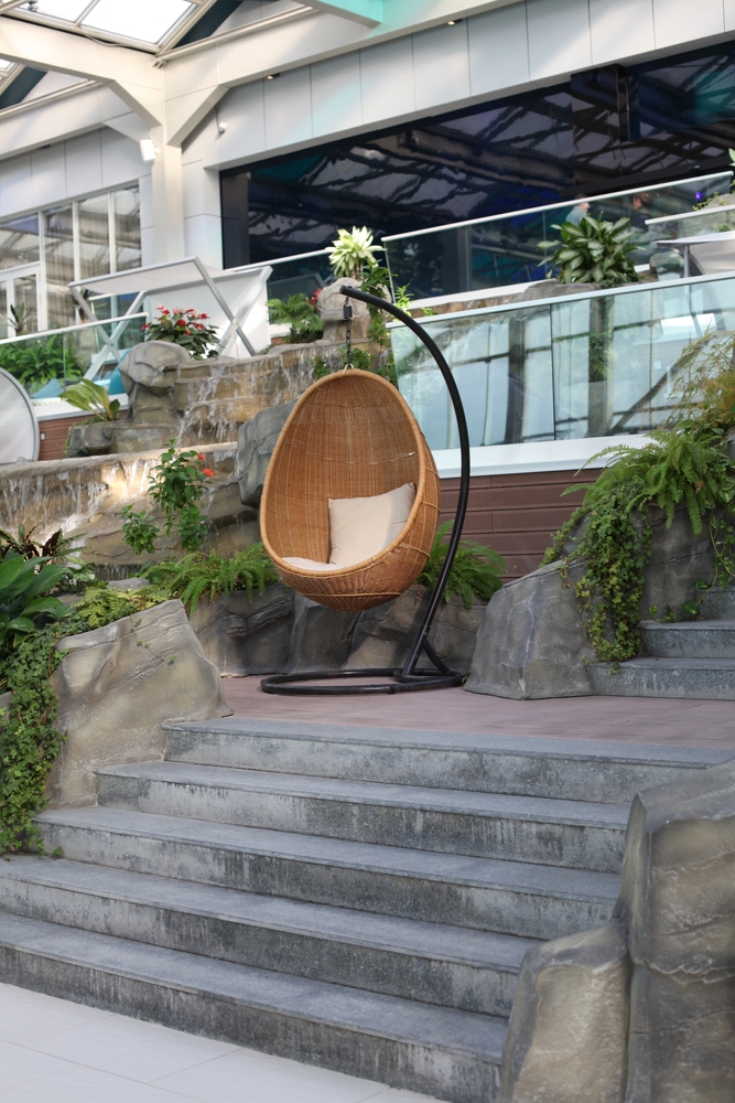 Rattan,Oval,Hanging,Chair,With,Pillow,In,Tropical,Plant.