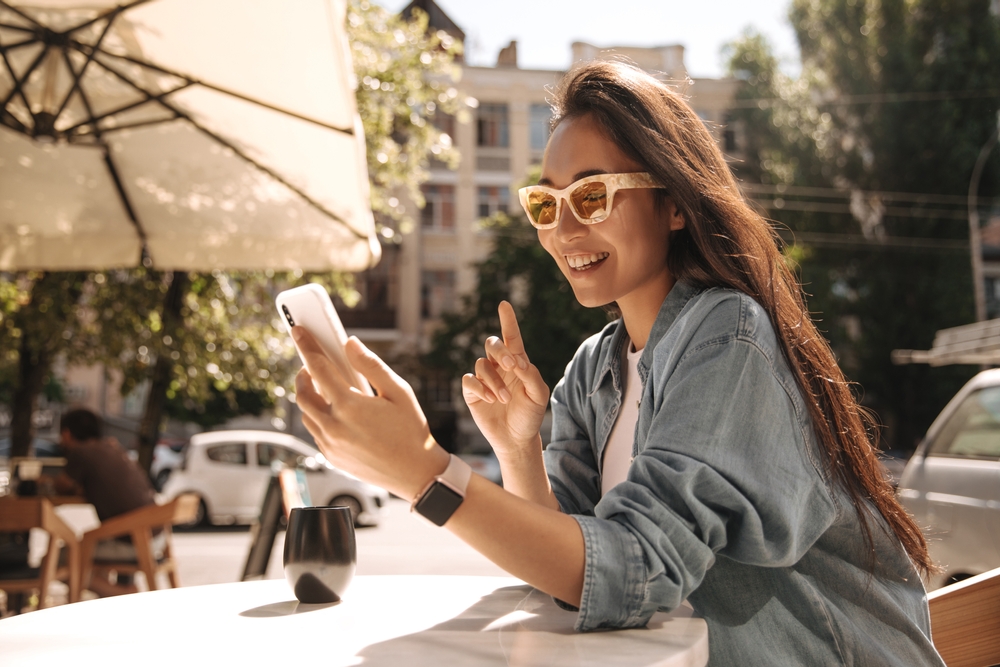 Cute,Young,Asian,Brunette,In,Glasses,Looking,At,Smartphone,Sitting