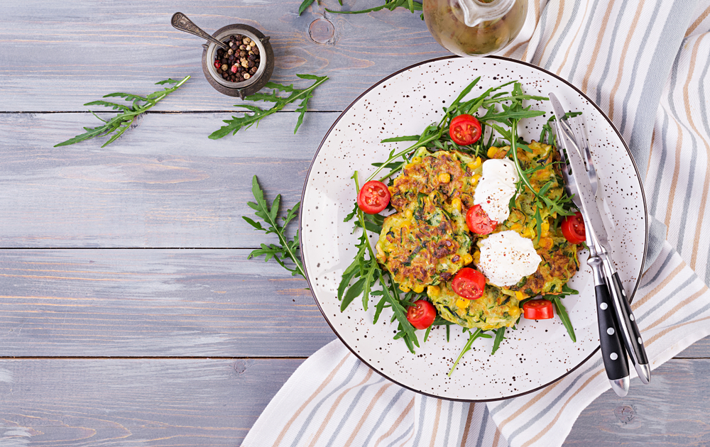 Zucchini,Pancakes,With,Corn,And,Sour,Cream,Served,Arugula,,Tomatoes