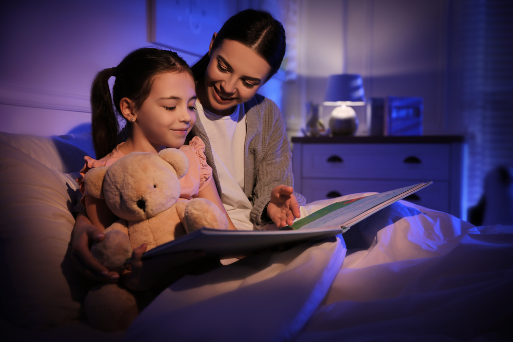 Mother,With,Little,Daughter,Reading,Fairy,Tale,In,Dark,Bedroom