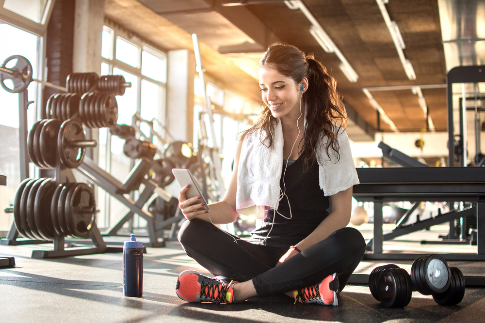 Young,Sporty,Woman,Listening,To,Music,On,Smartphone,In,Gym.