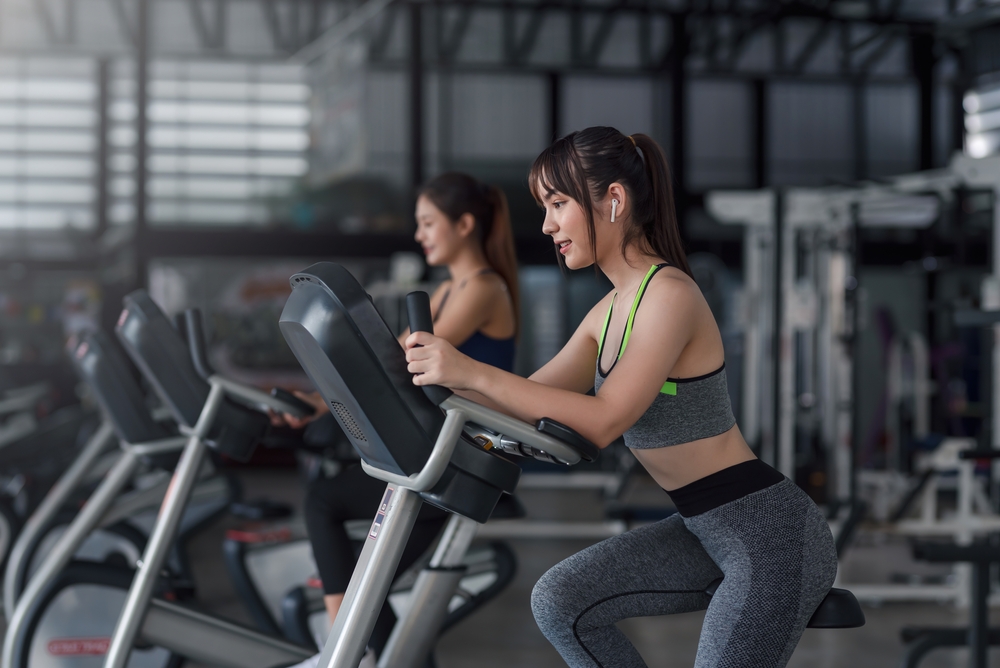 Young,Asian,Woman,Working,Out,On,Exercise,Bike,At,Gym.