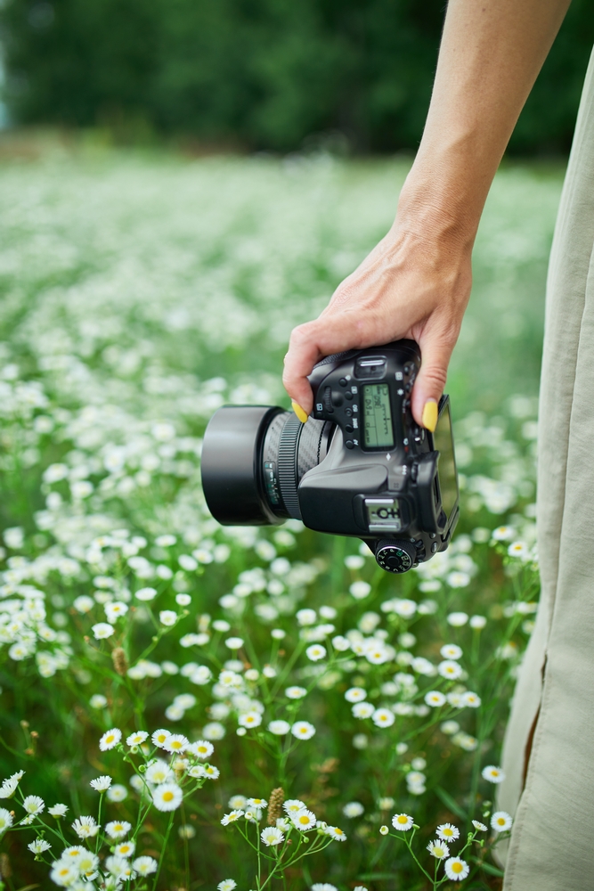 Female,Photographer,Holding,A,Camera,Outdoors,On,Flower,Field,Landscape,