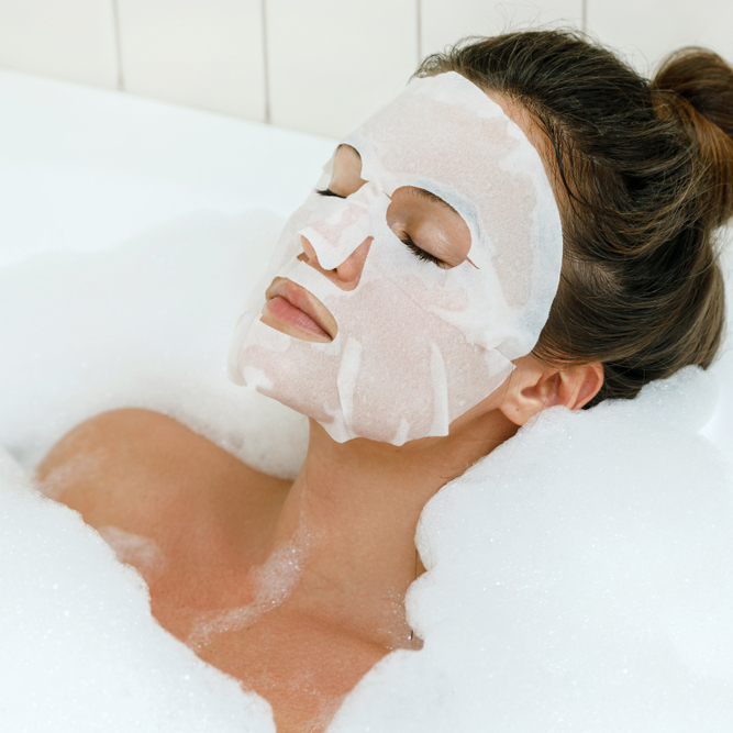 Woman,Lying,In,Bathtub,With,A,Sheet,Mask,On,Her