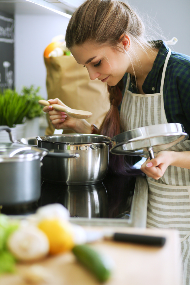 Young,Woman,Standing,By,The,Stove,In,The,Kitchen,.