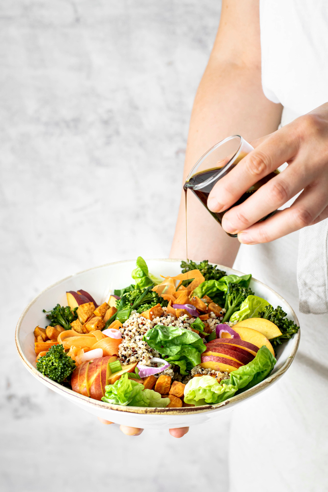 Woman,Pouring,Pumpkin,Seed,Oil,Over,Sweet,Potato,Buddha,Bowl