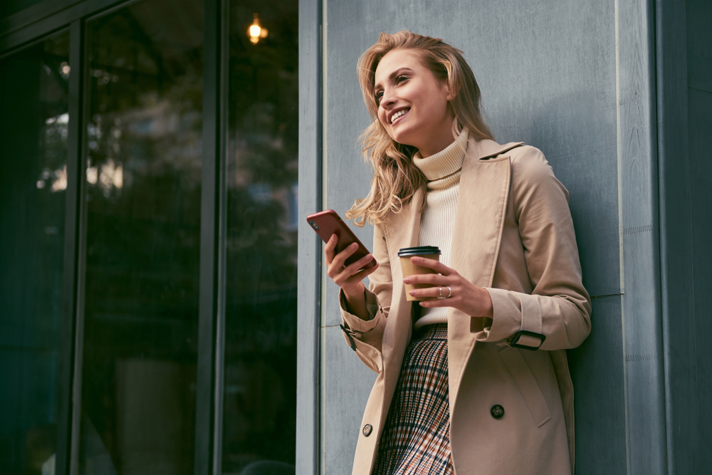 Attractive,Cheerful,Blond,Girl,In,Trench,Coat,With,Coffee,To