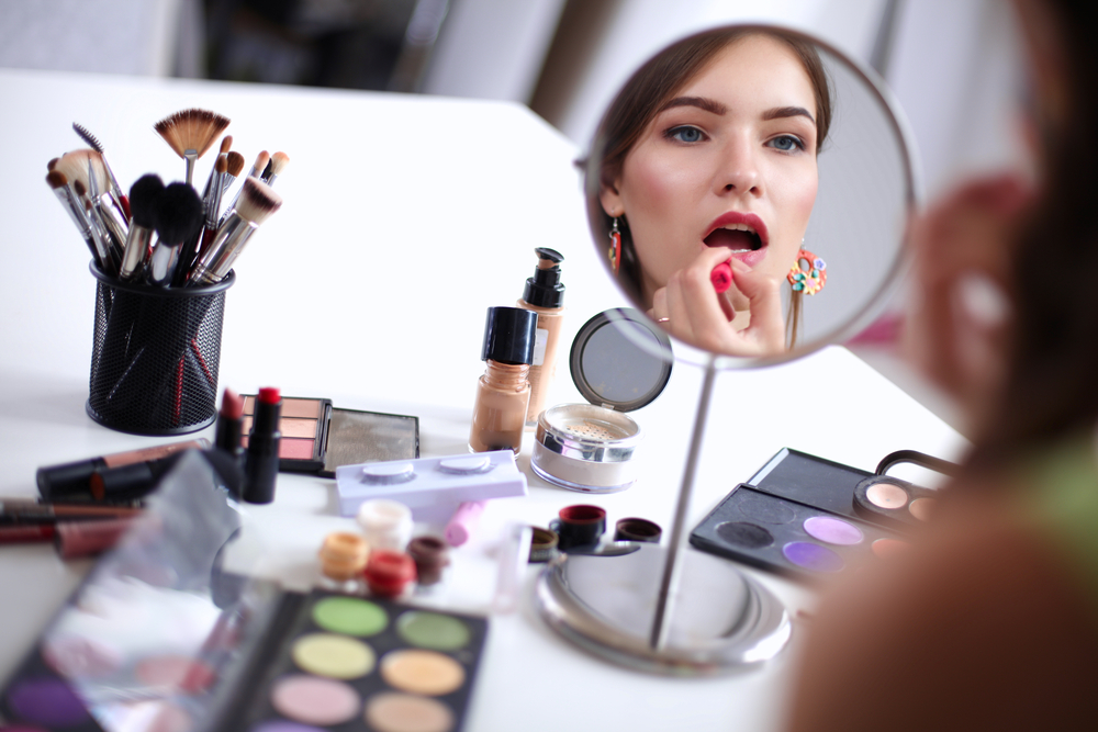 Young,Beautiful,Woman,Making,Make-up,Near,Mirror,sitting,At,The,Desk