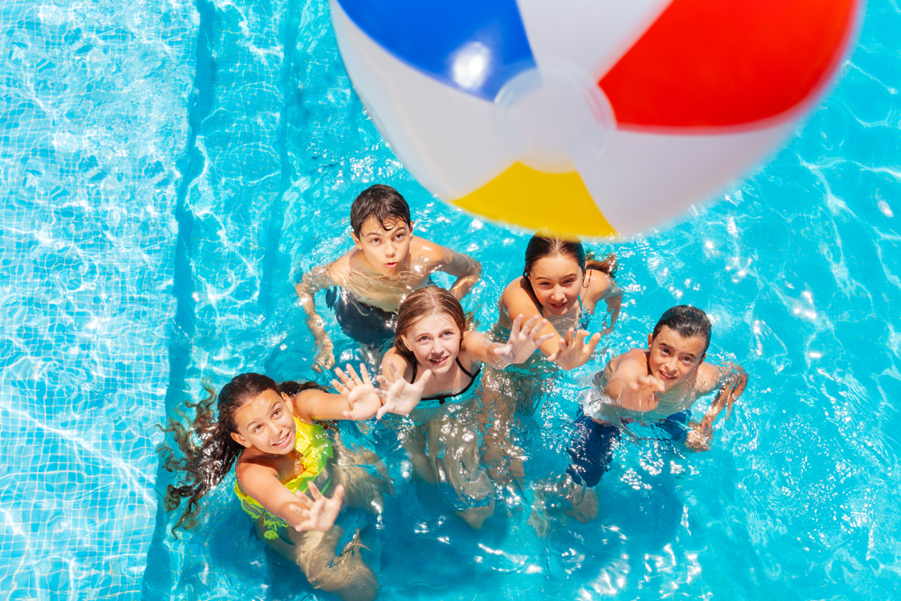 Many,Kids,In,Swimming,Pool,Play,With,Inflatable,Ball,View