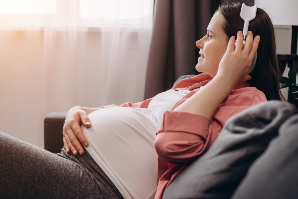 Close,Up,Of,Smiling,Young,Pregnant,Female,Applying,Headphones,On