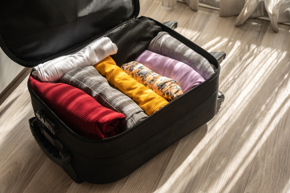 An,Opened,Suitcase,With,Colorful,Clothings,Pack,And,Arrange,Inside.