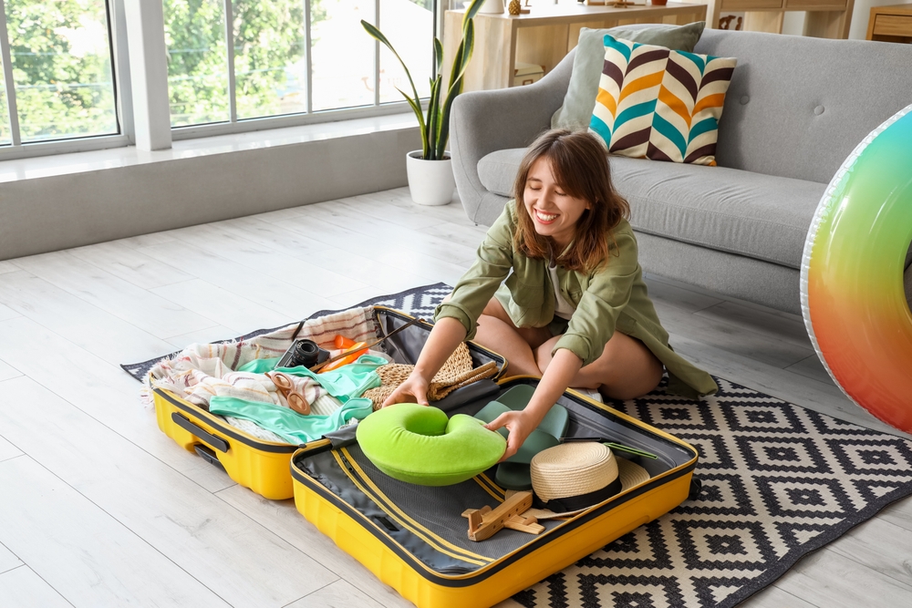 Young,Woman,Unpacking,Neck,Pillow,From,Suitcase,At,Home
