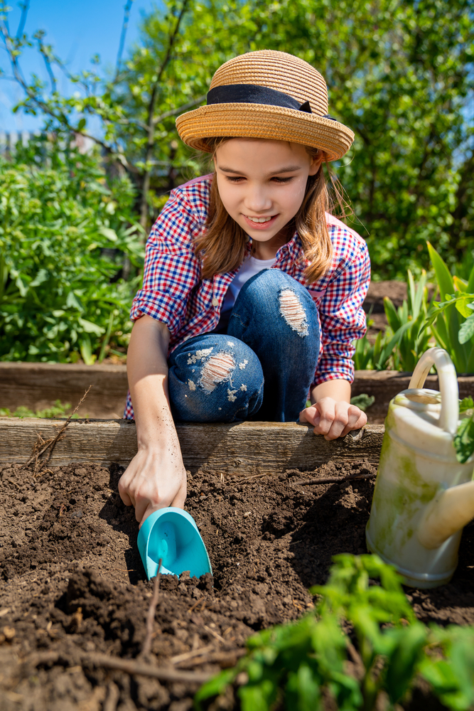 Little,Teen,Girl,In,A,Hat,Planting,Seedlings,In,Bed