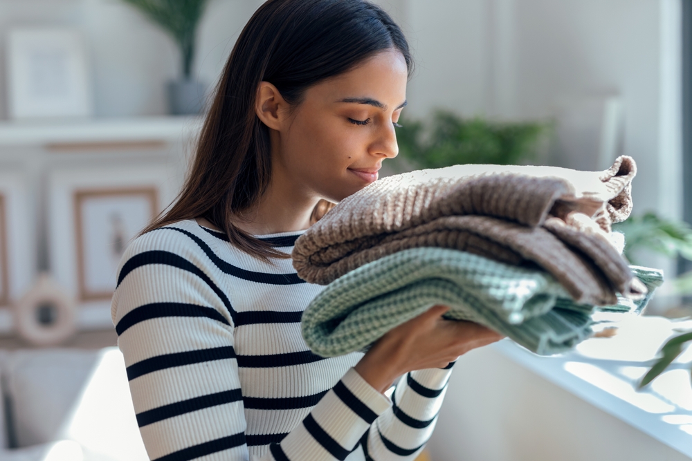 Shot,Of,Beautiful,Woman,Smelling,Clean,Laundry,After,Folding,In