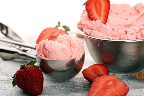 Strawberry ice cream scoop on a rustic white background with fresh strawberries