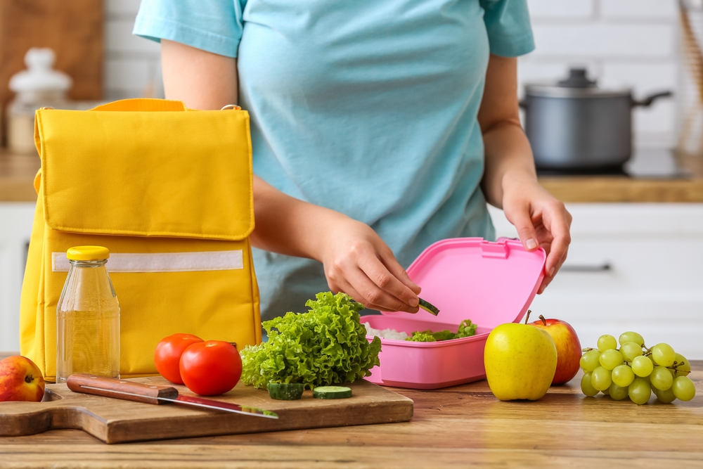Woman,Packing,Fresh,Meal,Into,Lunch,Box,In,Kitchen