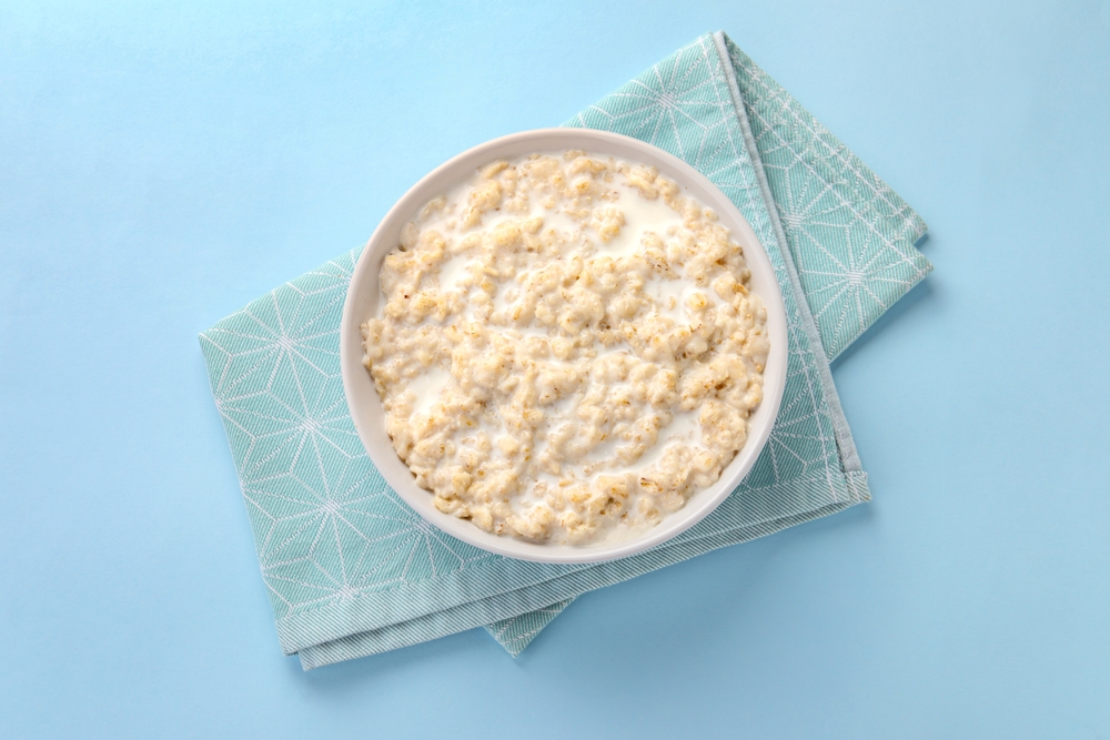 Tasty,Boiled,Oatmeal,In,Bowl,On,Light,Blue,Table,,Top