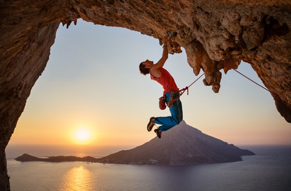 Male,Rock,Climber,Hanging,With,One,Hand,On,Challenging,Route